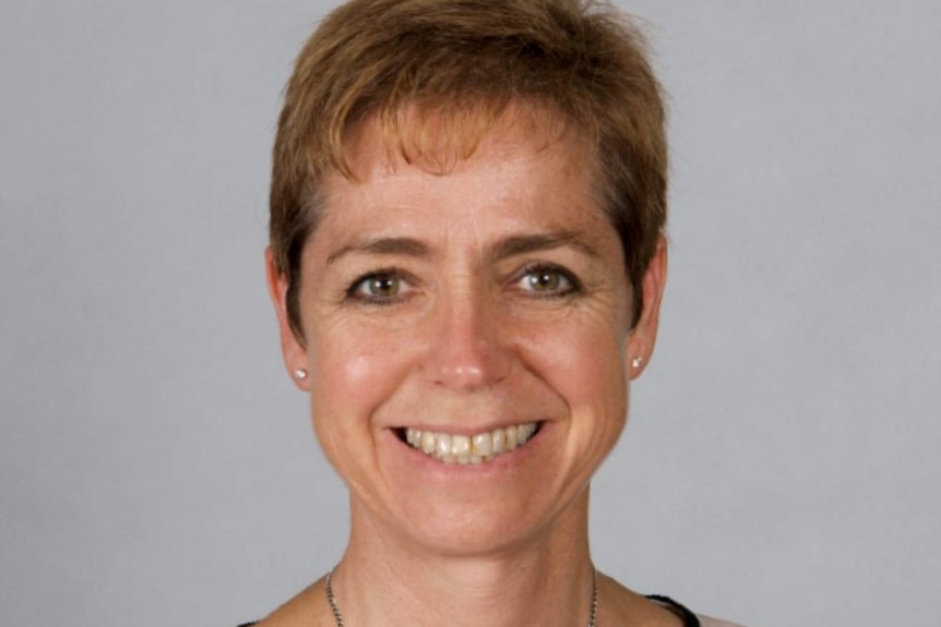 A school photo of a school principal with cropped hair and a button up top.