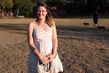 A young woman stands in a dig park in the afternoon.