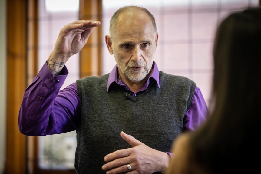 A middle-aged man gestures with his hands