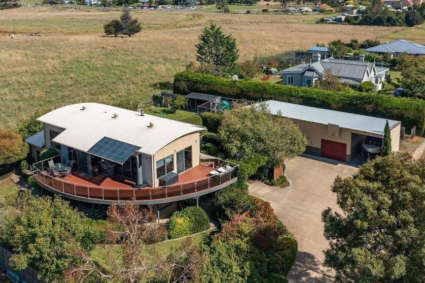 An elevated view of a property encircled by a verandah and open space.