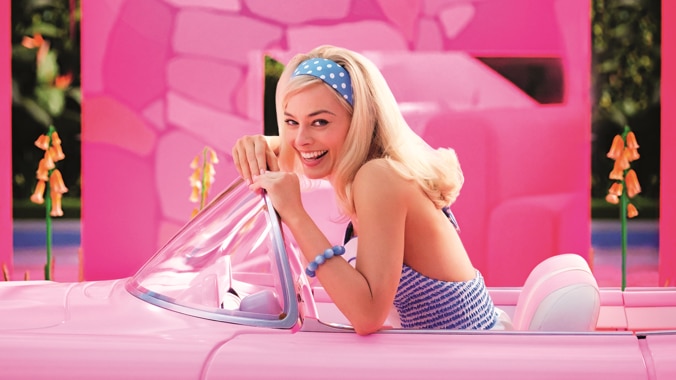 A screen grab from the Barbie movie shows a smiling blonde woman in a pink car, against a pink wall.