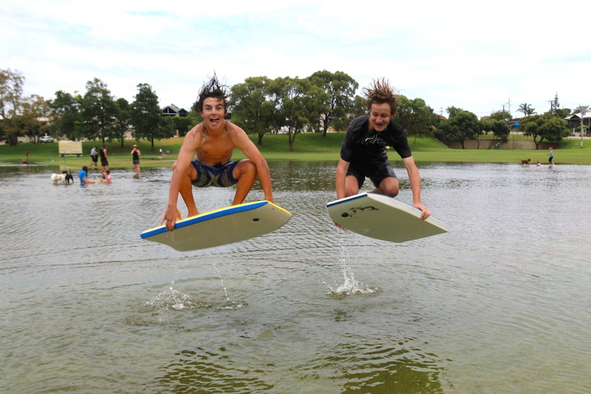 Two boys in mid-air on their bodyboards at a flooded park in the Perth suburb of Scarborough.