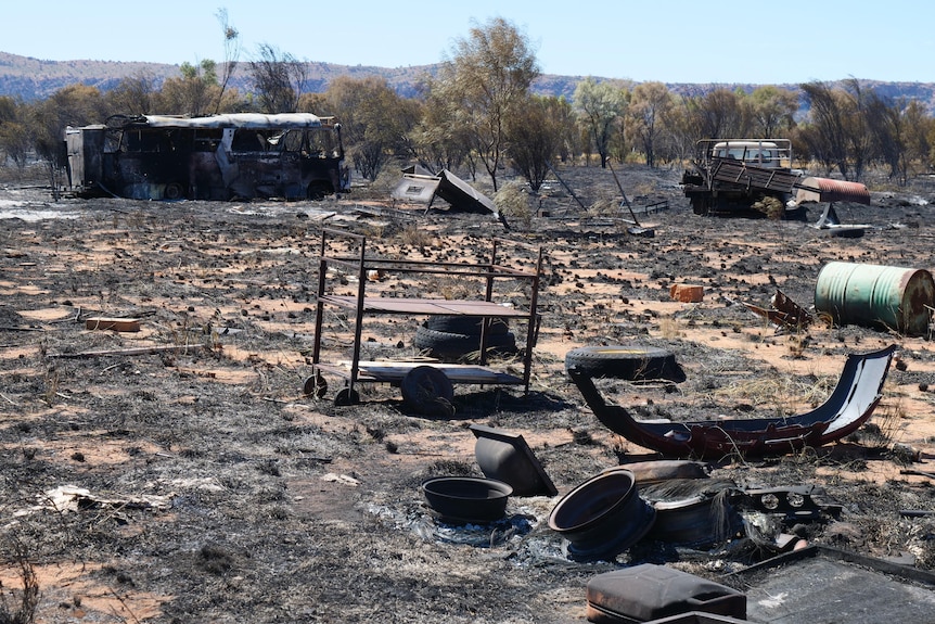 Burnt-out bus, cars and shrubs litter the scorched landscape.