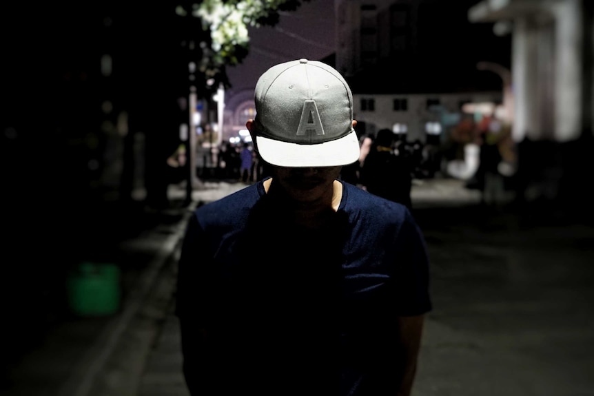 Dimas Alphareza poses for a photo in a dark street with his head down, making him unidentifiable.