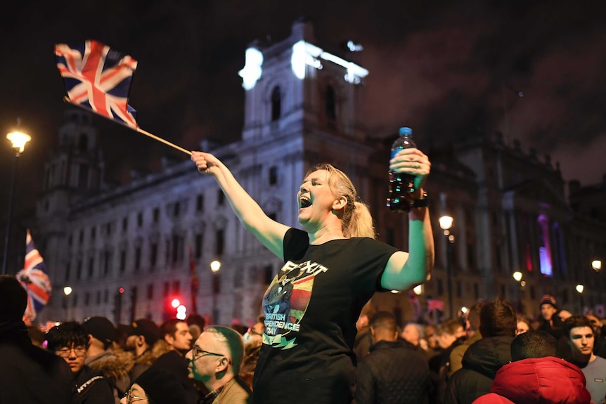 A woman holding an English flag waves it and yells