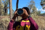 a student looks through a magnifying glass at the end of a hollowed log