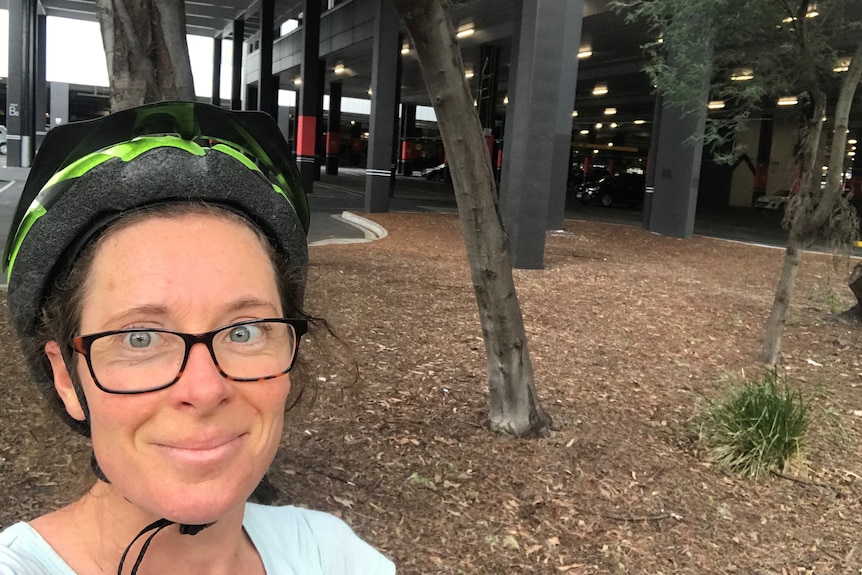 Nicola Thomas takes a selfie in front of a carpark while in her bicycle helmet.