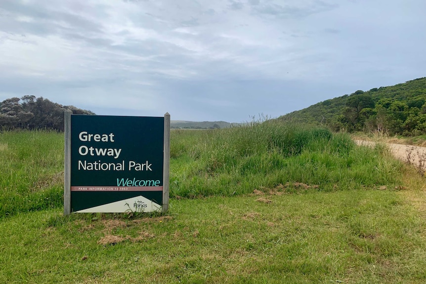 A sign reading 'Great Otway National Park, Welcome' in front of green grass and a grey-blue sky.