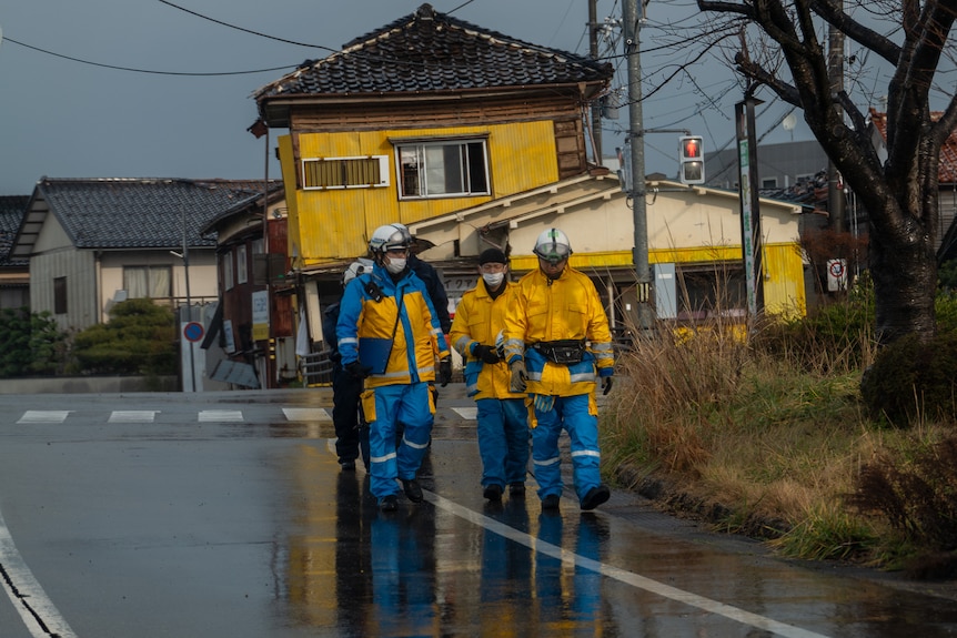 A group of men wearing yellow and blue uniforms are walking down a street. 