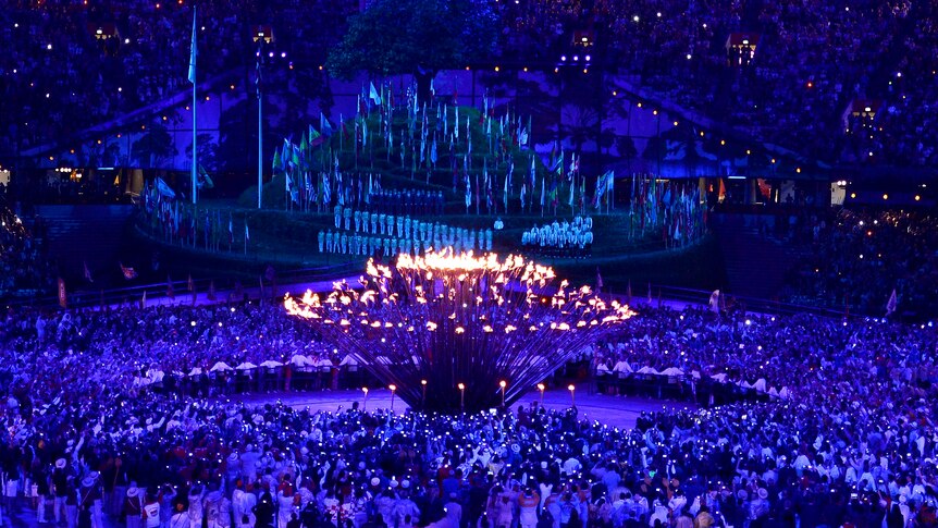 The stems of the Olympic flame come together to form one, lighting the cauldron.