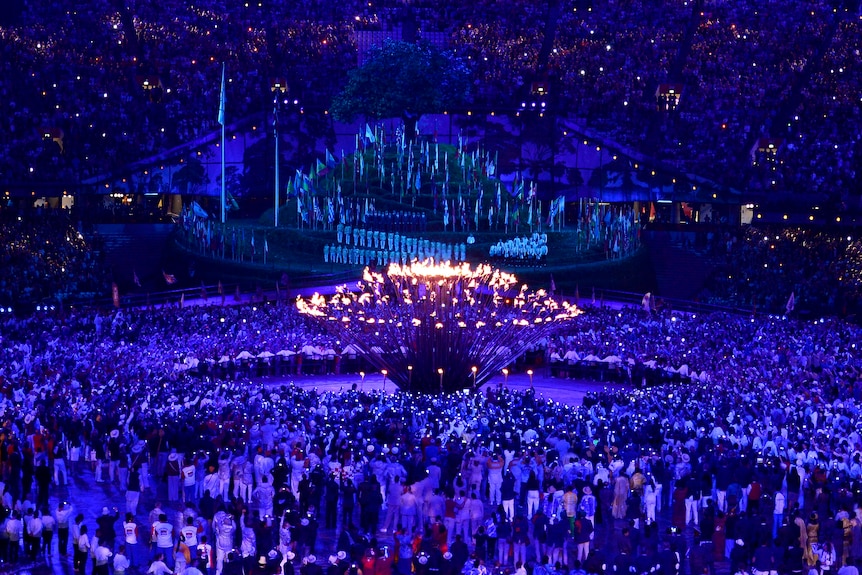 The stems of the Olympic flame come together to form one, lighting the cauldron.