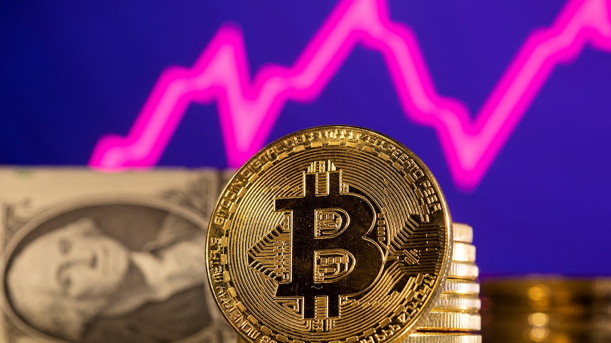 A representation of bitcoin is seen in front of a stock graph and US dollar 