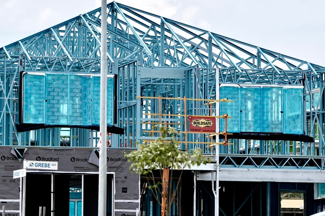 Vivienda en construcción, estructura de acero, tiene techo a dos aguas. Letrero de la calle en frente, Grebe Crt.