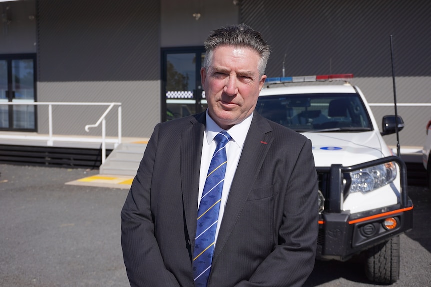 A man stands in front of a police car