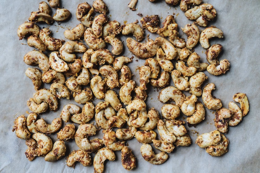 Cashews on baking tray that have been roasted with Thai red curry paste, shredded coconut and sea salt, for a pumpkin soup.