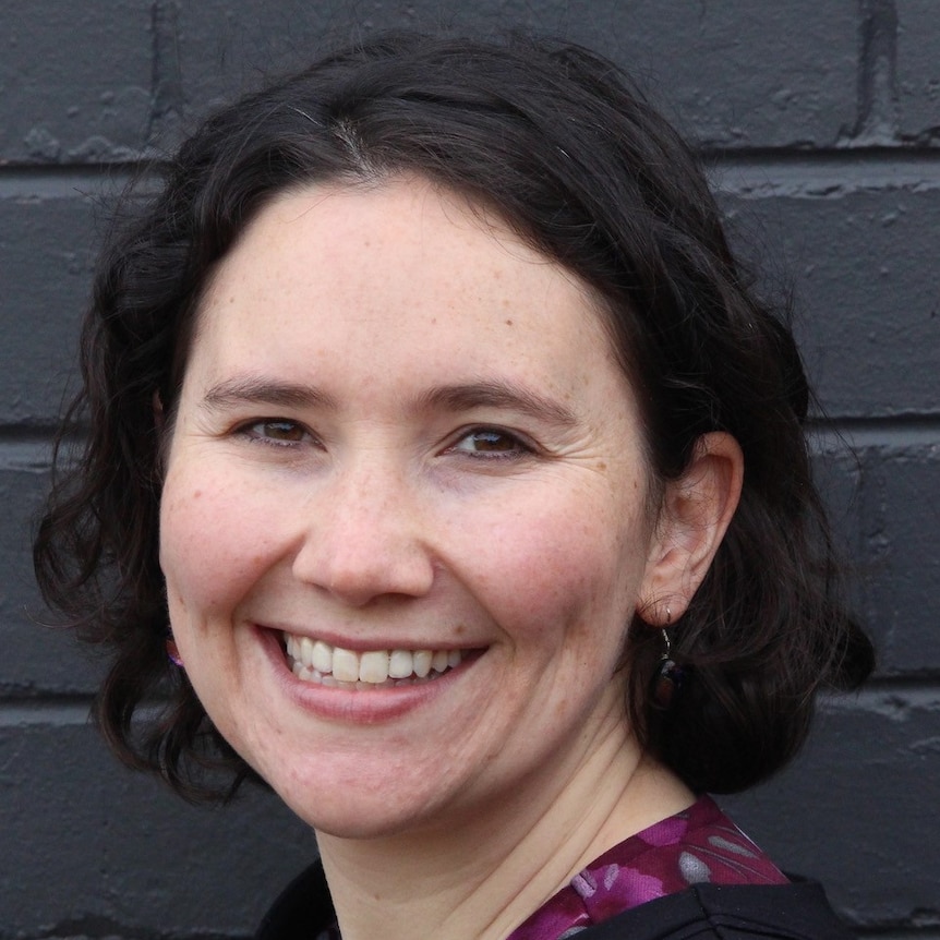 A headshot of a white woman with short brown hair smiling.