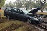 A car sits on tram tracks at Caulfield in Melbourne after sliding onto the tracks during wet weather.