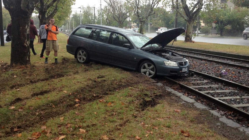 A car sits on tram tracks at Caulfield in Melbourne after sliding onto the tracks during wet weather.