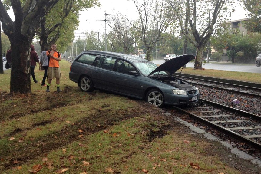 A car sits on tram tracks at Caulfield in Melbourne after sliding onto the tracks during wet weather.