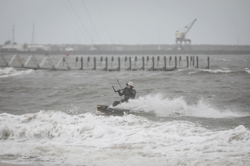 A kite surfer near the shore in rough, grey conditions.