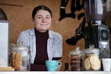 A young woman leans over the bar at coffee shop.