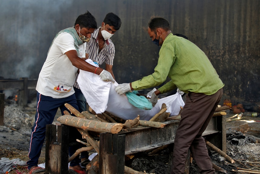 Relatives carry the body of a man, who died from the coronavirus disease, onto a funeral pyre.