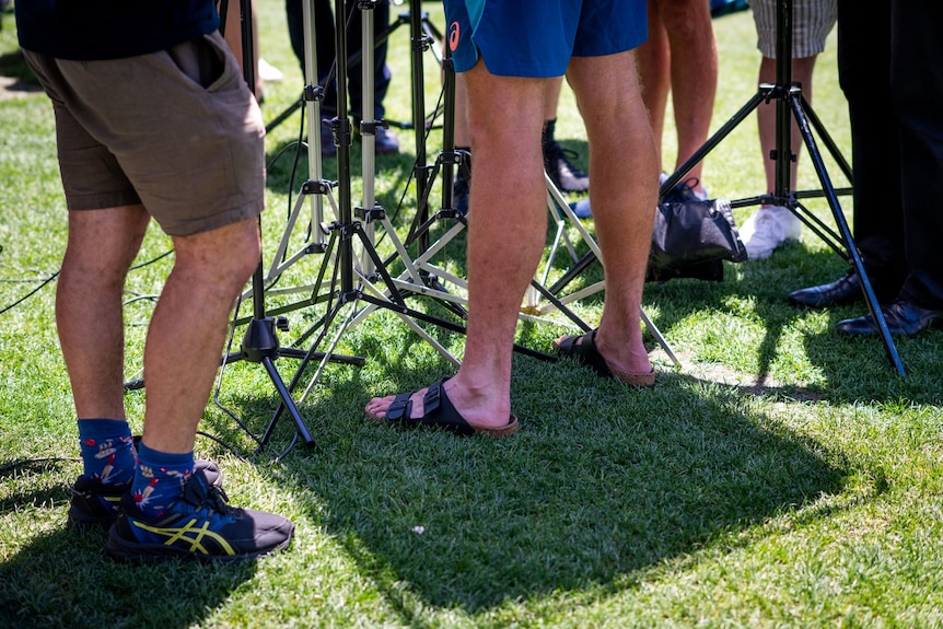 Shot of media legs and microphone stands on grass on outfield of the Adelaide Oval.