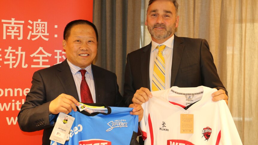 Xiu Zhentao and Keith Bradshaw hold cricket jumpers.