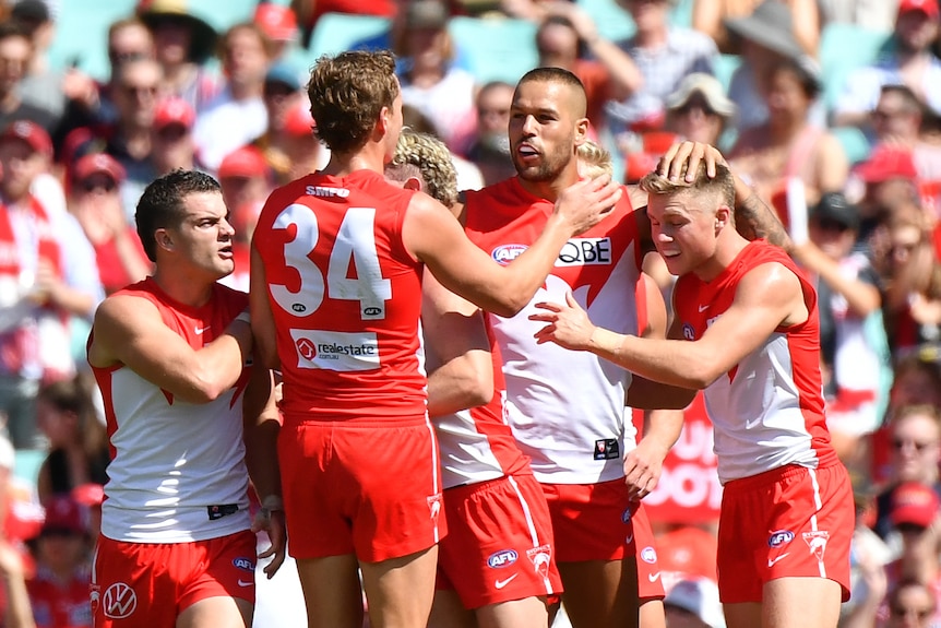 Un grupo de jugadores de Sydney Swans AFL se abrazan después de que se pateara un gol contra los Crows.