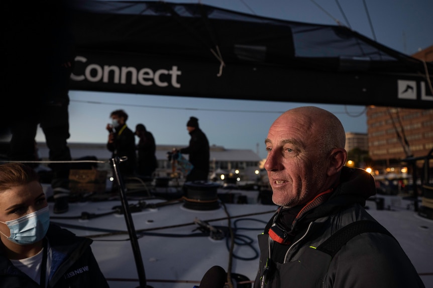 A man stands on a dock next to a large yacht.