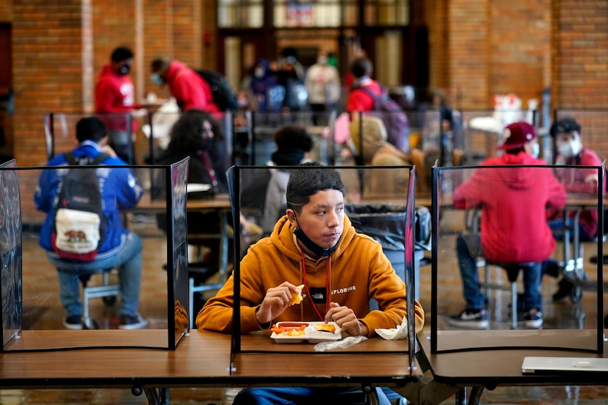 Classmates separated bv glass dividers at school in Kansas