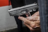 a close-up of a 9mm semi-automatic hangun held in a man's hand 