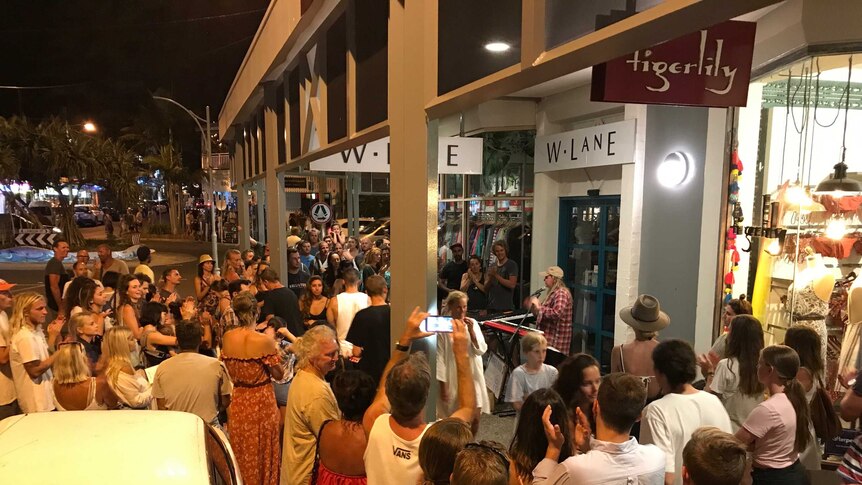 Woman busking with large crowd in Byron Bay