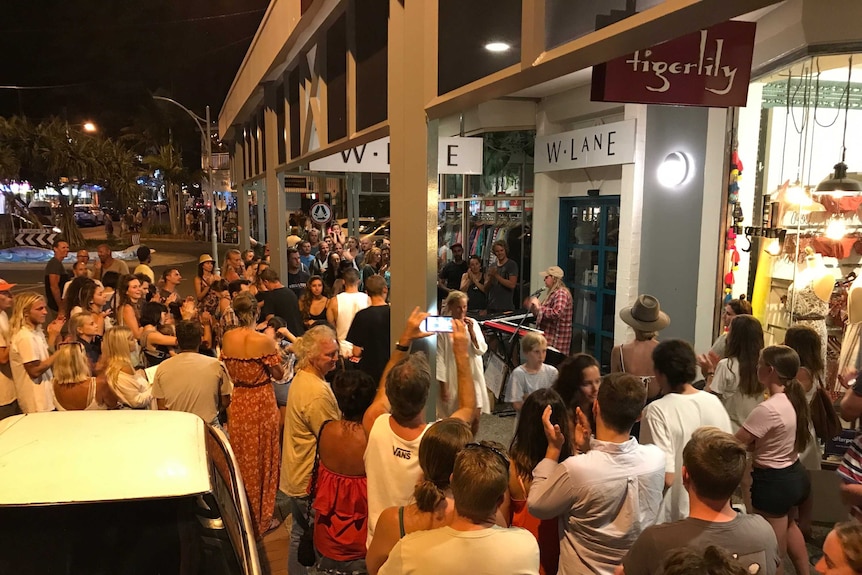 Woman busking with large crowd in Byron Bay
