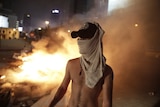 Lebanese protester amid chaos with fire and smoke behind him.
