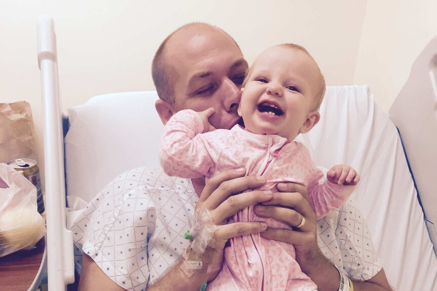 Adam Harvey with his daughter Isla in hospital after having a bullet removed from his neck