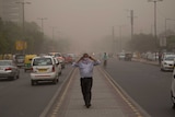 A man wraps a scarf around his nose as a dust storm envelops the city in New Delhi