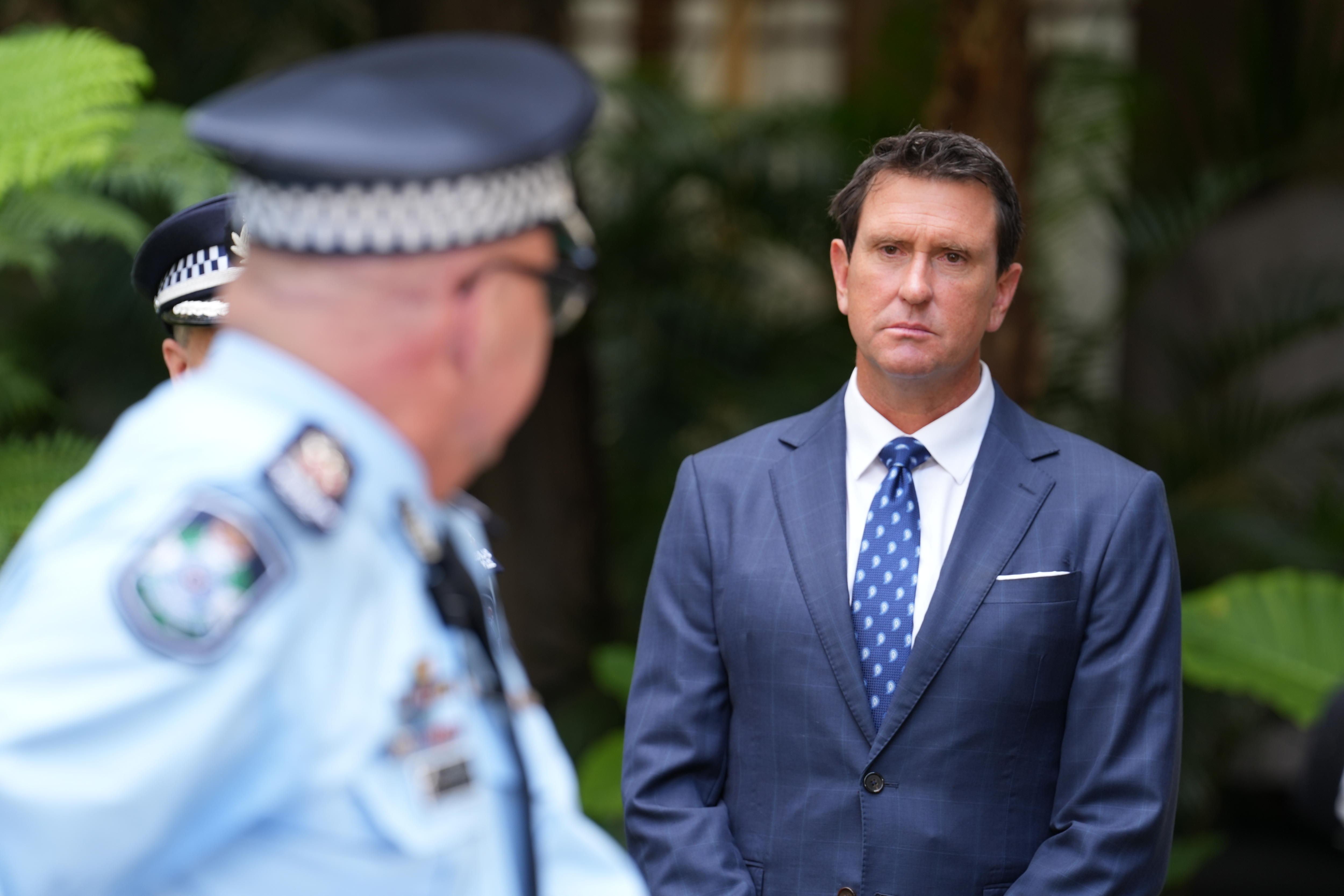 Um policial se vira para olhar para um homem de terno em uma entrevista coletiva.