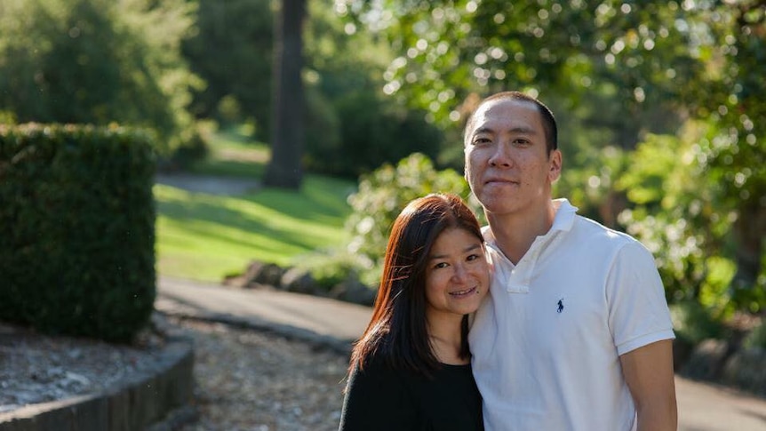 Helen Wong stands next to her husband in a park.