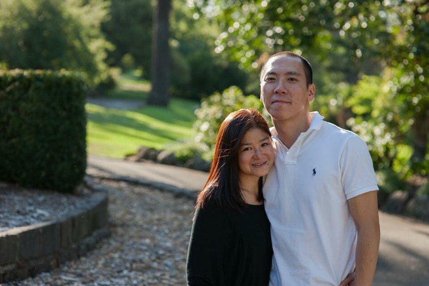 Helen Wong stands next to her husband in a park.