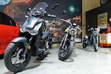 Three electric motorbikes are lined up in a showroom.