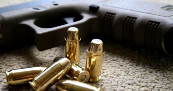 A gun sits next to golden coloured bullets.