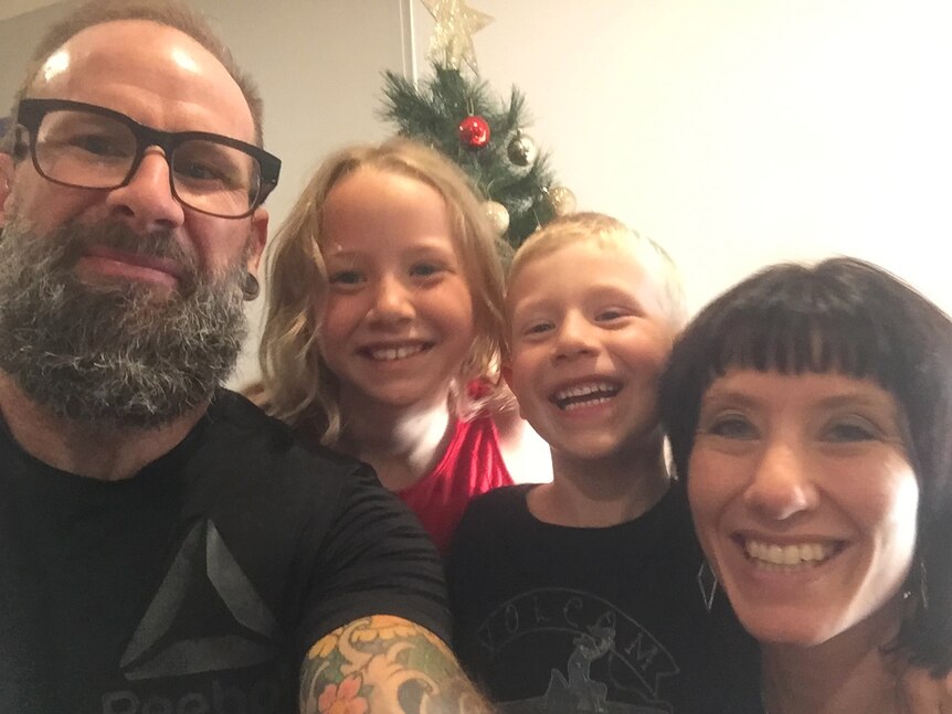 A smiling family of four, with Christmas decorations in the background.