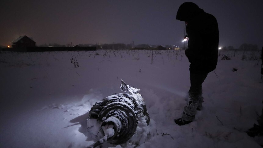 A man stands near part of the plane that crashed after taking off from Moscow's Domodedovo airport on February 11, 2018.