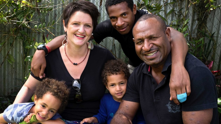 A family portrait of an Anglo-Saxon woman with a Papua New Guinean man and three of their children.
