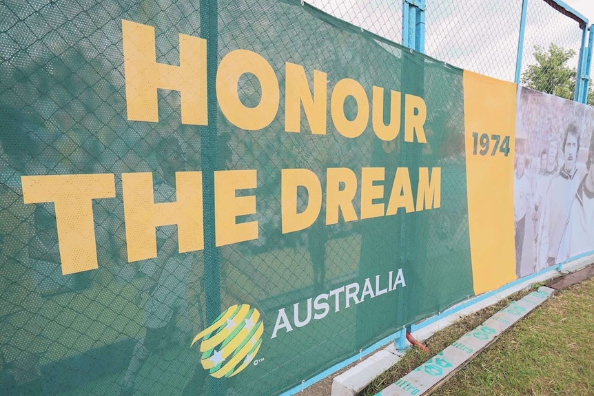 Banners bearing the slogan honour the Dream are attatched to a chain link fence on grass.