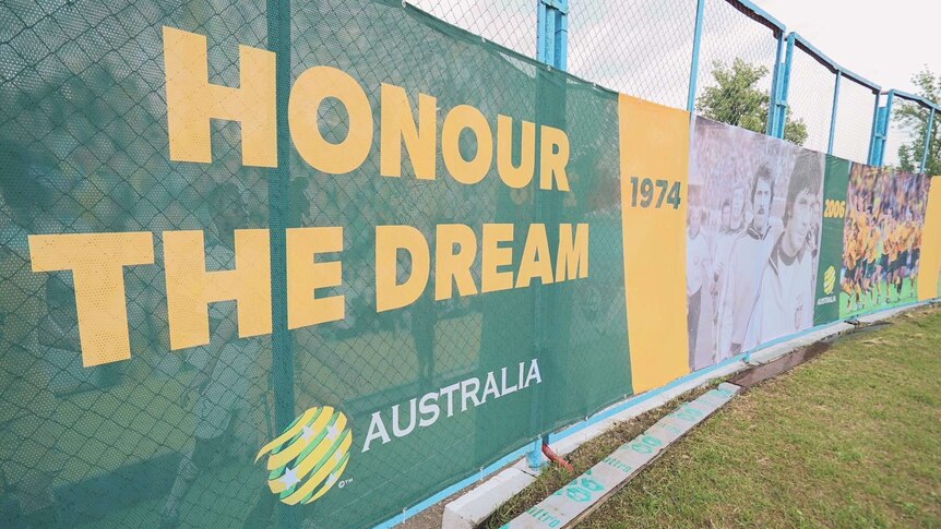 Banners bearing the slogan honour the Dream are attatched to a chain link fence on grass.