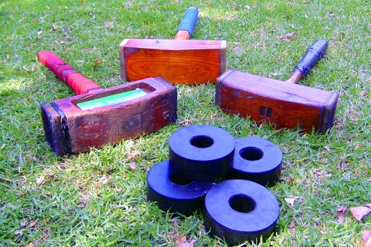 Three Trugo mallets and four rings lay on the grass.