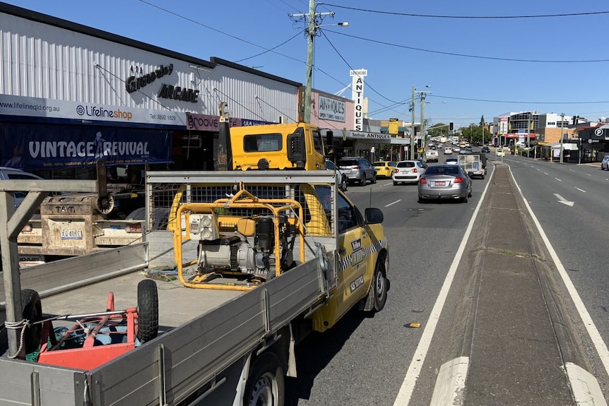 Cars drive past shops along Ipswich Road.