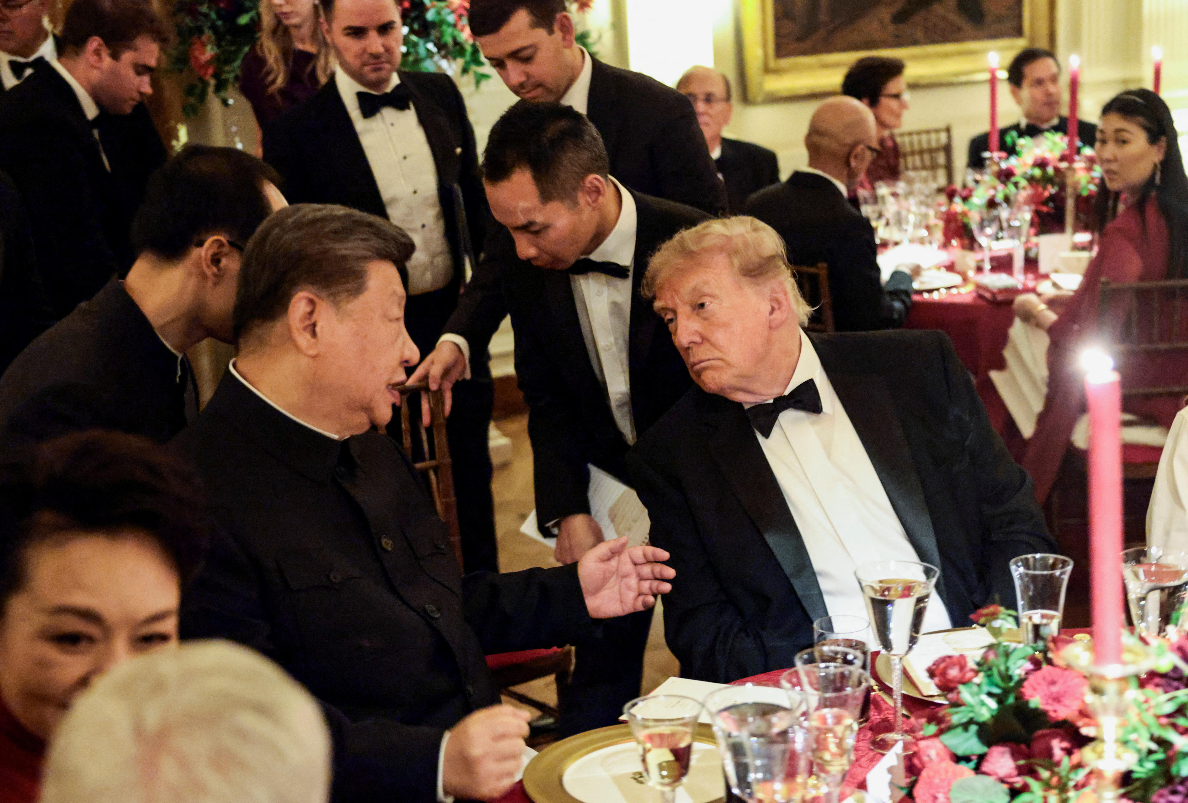 In a packed dinner room, two men exchange a friendly but quiet word.